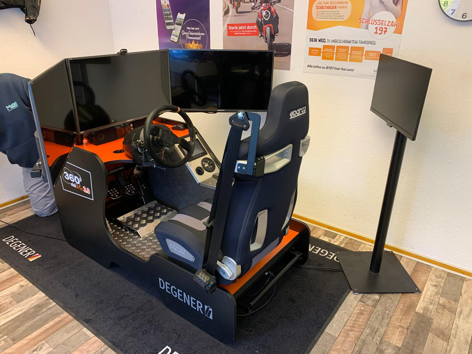 Ein moderner Fahrsimulator mit schwarzem Sportsitz und mehreren Bildschirmen